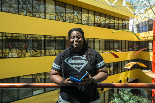 Male student standing infront of railing overlooking the interior of the Alief Hayes Campus